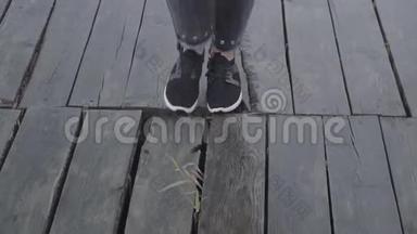 穿着运动鞋和黑裤子的女人走在潮湿的木板码头上